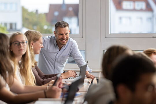 Gemeinschaflich Lernen in kleinen Gruppen an der Berufsfachschule Wirtschaft. Ein Lehrer erklärt einer Schülerin eine Aufgabe an der Berufsfachschule Wirtschaft.